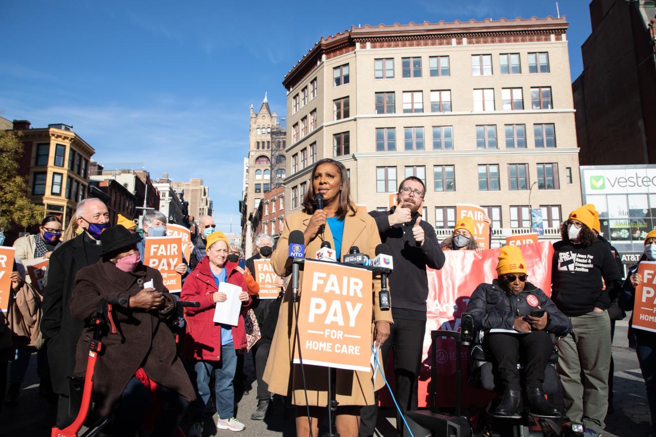 AG James stands at a microphone addressing the public at a Fair Pay rally